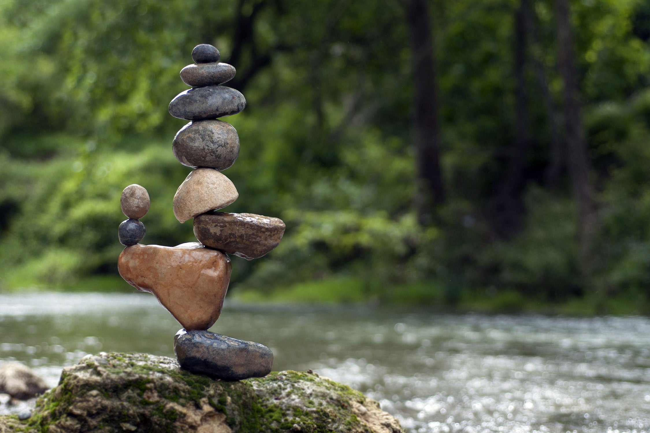 Balanciertes Steinkunstwerk am Fluss, Glasbild